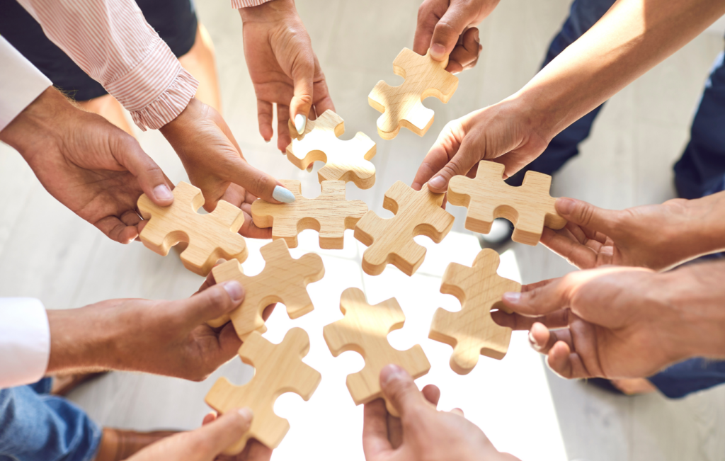 hands bringing together large wooden puzzle pieces